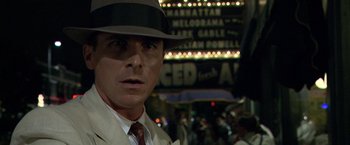 Movie still from “Public Enemies” (2009), directed by Michael Mann – A man wearing a suit and a hat in front of a crowd; Close Up shot, Over the shoulder angle
