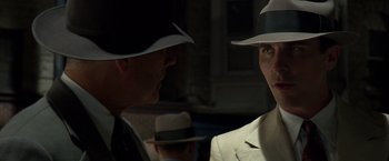 Movie still from “Public Enemies” (2009), directed by Michael Mann – A man in a white suit and a man in a white hat; Close Up shot, Over the shoulder angle