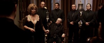 Movie still from “Punisher: War Zone” (2008), directed by Lexi Alexander – A group of men and a woman standing in front of a chair; Medium shot, High angle