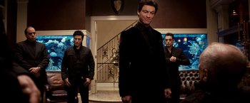 Movie still from “Punisher: War Zone” (2008), directed by Lexi Alexander – A group of men standing next to each other in front of a staircase; Medium shot, Low angle