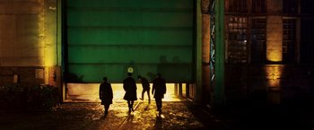 Movie still from “Punisher: War Zone” (2008), directed by Lexi Alexander – A group of people walking in the dark near a building; Extreme Wide shot, Low angle