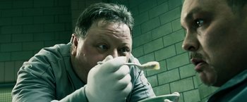 Movie still from “Punisher: War Zone” (2008), directed by Lexi Alexander – A man wearing gloves and holding a plate with a tooth brush; Close Up shot, Low angle