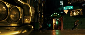 Movie still from “Punisher: War Zone” (2008), directed by Lexi Alexander – A green neon sign is lit up at night; Wide shot, Low angle