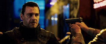 Movie still from “Punisher: War Zone” (2008), directed by Lexi Alexander – A man holding a gun while standing next to another man; Close Up shot, Low angle
