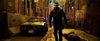 Movie still from “Punisher: War Zone” (2008), directed by Lexi Alexander – A man walking down a street next to a parked car; Wide shot, Low angle