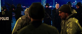 Movie still from “Punisher: War Zone” (2008), directed by Lexi Alexander – A group of people standing next to each other on a street; Medium shot, Over the shoulder angle