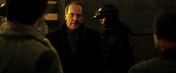 Movie still from “Punisher: War Zone” (2008), directed by Lexi Alexander – A man in a suit and tie standing next to a man in a uniform; Close Up shot, Over the shoulder angle