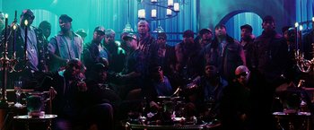 Movie still from “Punisher: War Zone” (2008), directed by Lexi Alexander – A group of men sitting around a table in front of a chandelier; Wide shot, High angle