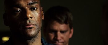 Movie still from “Punisher: War Zone” (2008), directed by Lexi Alexander – Two men are standing side by side in the dark; Close Up shot, Over the shoulder angle