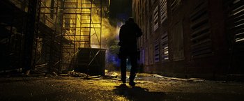 Movie still from “Punisher: War Zone” (2008), directed by Lexi Alexander – A man standing in the dark in front of a building; Wide shot, Low angle