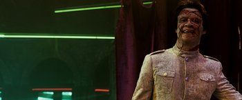 Movie still from “Punisher: War Zone” (2008), directed by Lexi Alexander – A man wearing a suit and tie standing in front of a curtain; Medium shot, Low angle