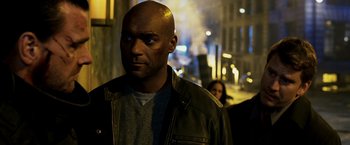 Movie still from “Punisher: War Zone” (2008), directed by Lexi Alexander – A man in a leather jacket standing in the street; Close Up shot, Over the shoulder angle