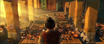 Movie still from “Puss in Boots” (2011), directed by Chris Miller – A group of people sitting around plates on a wooden floor; Wide shot, High angle