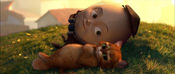 Movie still from “Puss in Boots” (2011), directed by Chris Miller – An orange cat laying next to a toy doll; Close Up shot, Low angle