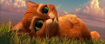 Movie still from “Puss in Boots” (2011), directed by Chris Miller – An orange cat laying in the grass with its eyes wide open; Close Up shot, High angle