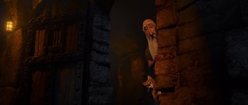 Movie still from “Puss in Boots” (2011), directed by Chris Miller – A man with a beard and a hat looking over a wall; Medium shot, Low angle