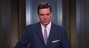Movie still from “Quiz Show” (1994), directed by Robert Redford – A man wearing a suit and tie standing in front of a window; Close Up shot, Low angle