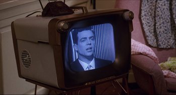 Movie still from “Quiz Show” (1994), directed by Robert Redford – An old television with a picture of a man on it; Close Up shot, Over the shoulder angle