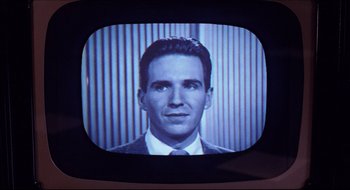 Movie still from “Quiz Show” (1994), directed by Robert Redford – A man in a suit and tie on a television screen; Extreme Close Up shot, Low angle