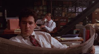 Movie still from “Quiz Show” (1994), directed by Robert Redford – A man sitting in front of another man in a library; Medium shot, High angle