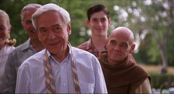 Movie still from “Quiz Show” (1994), directed by Robert Redford – A group of people standing next to each other in a park; Close Up shot, Over the shoulder angle