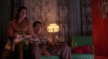 Movie still from “Quiz Show” (1994), directed by Robert Redford – A man and a woman sitting on a green couch; Medium shot, Low angle