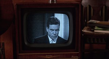 Movie still from “Quiz Show” (1994), directed by Robert Redford – A man in a suit and tie on a television screen; Close Up shot, Over the shoulder angle