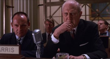 Movie still from “Quiz Show” (1994), directed by Robert Redford – An older man sitting at a table next to a microphone; Medium shot, Low angle