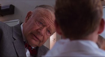Movie still from “Quiz Show” (1994), directed by Robert Redford – An older man wearing a suit and tie looking at a young boy; Close Up shot, Over the shoulder angle