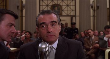 Movie still from “Quiz Show” (1994), directed by Robert Redford – A man in a suit and tie with a microphone; Close Up shot, Low angle