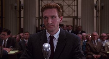 Movie still from “Quiz Show” (1994), directed by Robert Redford – A man wearing a suit and tie holding a microphone; Close Up shot, Low angle