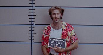 Movie still from “Raising Arizona” (1987), directed by Joel Coen – A man in a hawaiian shirt holding up a sign; Medium shot, Low angle