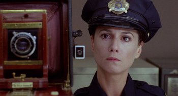 Movie still from “Raising Arizona” (1987), directed by Joel Coen – A woman in a police officer's uniform looking to her left; Close Up shot, Low angle