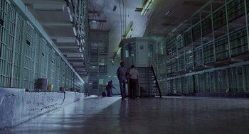 Movie still from “Raising Arizona” (1987), directed by Joel Coen – Two men are standing in a room next to stairs; Extreme Wide shot, High angle