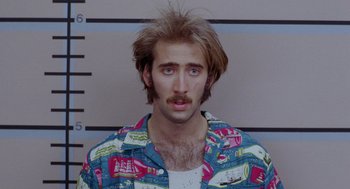 Movie still from “Raising Arizona” (1987), directed by Joel Coen – A mugshot of a man with a beard and mustache; Close Up shot, Overhead angle