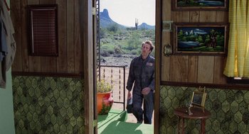Movie still from “Raising Arizona” (1987), directed by Joel Coen – A man standing in front of an open door; Wide shot, Over the shoulder angle