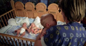 Movie still from “Raising Arizona” (1987), directed by Joel Coen – A man holding a baby in his arms while another baby lies in a bed; Medium shot, Overhead angle