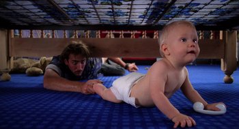 Movie still from “Raising Arizona” (1987), directed by Joel Coen – A man and a baby laying under a bed; Medium shot, High angle