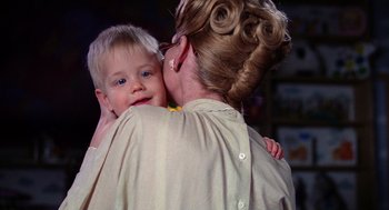 Movie still from “Raising Arizona” (1987), directed by Joel Coen – A woman is holding a young boy in her arms; Close Up shot, Over the shoulder angle