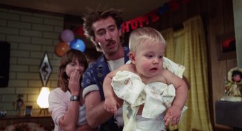 Movie still from “Raising Arizona” (1987), directed by Joel Coen – A man holding a baby while a woman looks on; Medium shot, Low angle