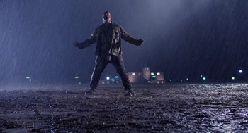 Movie still from “Raising Arizona” (1987), directed by Joel Coen – A man standing in the middle of a field in the rain; Wide shot, Low angle