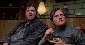 Movie still from “Raising Arizona” (1987), directed by Joel Coen – A couple of men sitting next to each other eating food; Close Up shot, Low angle