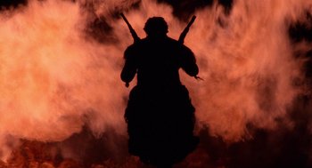 Movie still from “Raising Arizona” (1987), directed by Joel Coen – A silhouette of a person holding two guns; Wide shot, Low angle