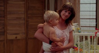 Movie still from “Raising Arizona” (1987), directed by Joel Coen – A woman holding a baby in her arms and smiling; Medium shot, Over the shoulder angle