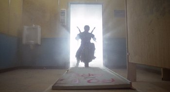 Movie still from “Raising Arizona” (1987), directed by Joel Coen – A person on a motorcycle in a room with a door open; Wide shot, Low angle