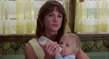 Movie still from “Raising Arizona” (1987), directed by Joel Coen – A woman holding a baby while holding a bottle of milk; Close Up shot, Low angle