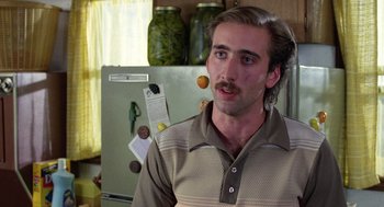 Movie still from “Raising Arizona” (1987), directed by Joel Coen – A man in a brown and white striped shirt is in front of a refrigerator; Close Up shot, Low angle