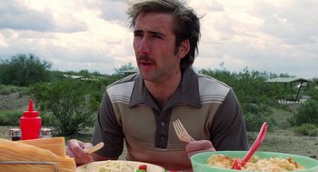 Movie still from “Raising Arizona” (1987), directed by Joel Coen – A man sitting at a table with a plate of food in front of him; Close Up shot, Over the shoulder angle