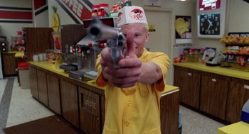 Movie still from “Raising Arizona” (1987), directed by Joel Coen – A man in a burger king uniform points a gun at the camera; Medium shot, Low angle