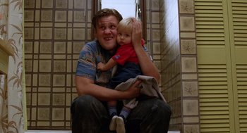 Movie still from “Raising Arizona” (1987), directed by Joel Coen – A man and a child sitting on the ground; Medium shot, Low angle